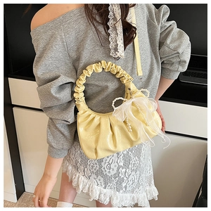Détail du sac à main plissé jaune pâle avec chaîne de perles et nœud en résille
