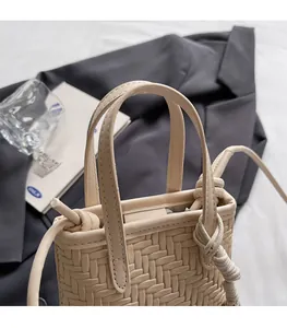 Close-up of beige woven leather crossbody bag with knot detail and sleek top handles