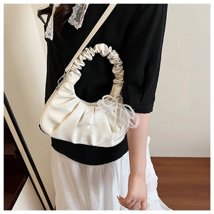 Détail du sac nuage plissé beige avec pendentif nœud en perles et poignée à froufrous