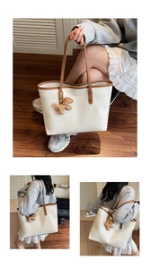 Detail of white crocodile textured tote bag with brown handles and a puppy charm