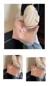 Detailed close-up of pink leather tote bag with cute dog charm on indoor stairs