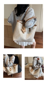 Detail of cream faux crocodile tote bag with brown straps and cute bear charm
