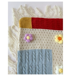 Close-up of bohemian knit tote bag showing colorful color block patterns and floral details