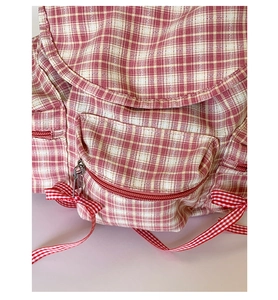 Détail du sac à dos à carreaux roses avec poche zippée et nœud papillon décoratif doux
