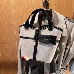 Secchiello in tela e pelle con etichetta FASHION mostrato su un trench