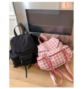 Détail de sacs à dos à carreaux avec plusieurs poches zippées et décoration de nœud