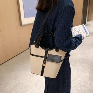 Borsa a secchiello in tela retrò con finiture in pelle nera e tracolla su modella
