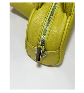Détail de la texture cuir litchi vert citron avec une fermeture éclair argentée du sac