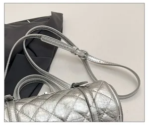 Détail de la bandoulière argentée réglable avec boucle sur le sac matelassé