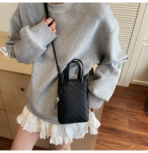Detail of hand-woven black leather mini crossbody phone bag with round handle