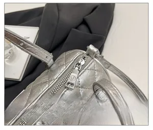 Détail du sac à bandoulière matelassé argenté avec fermeture éclair métallique lisse