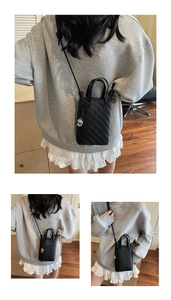 Detail of black woven mini crossbody bag with knot strap and silver heart pendant