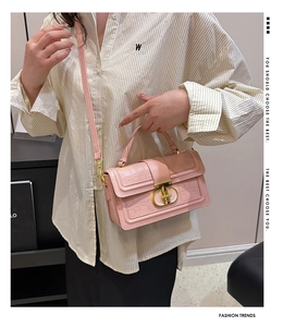 Detailed view of pink crocodile pattern box bag with golden clasp worn by model