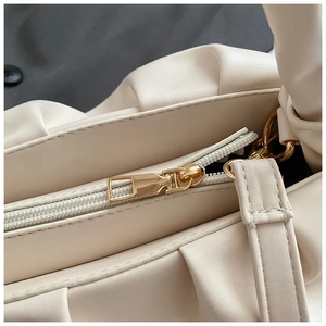 Detail of beige pleated cloud bag featuring premium gold zipper and soft texture