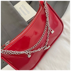 Detail of red patent leather shoulder bag with silver chains and heart pendants