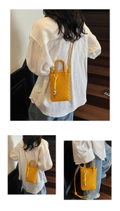 Detailed close-up of yellow woven mini phone bag with chic silver heart pendant detail