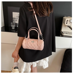Détail du sac cylindrique matelassé rose avec chaîne en métal et fermoir pivotant