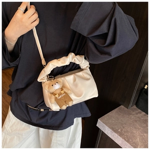 Detail of cream pleated cloud bag with soft ruffle handle and cute bear charm pendant