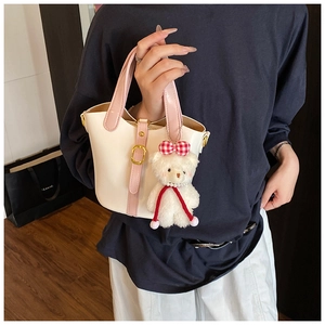 Detail view of pink and beige leather bucket bag featuring a cute teddy bear charm