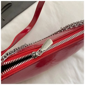 Close-up of bright red patent leather handbag with silver zipper and brand logo detail