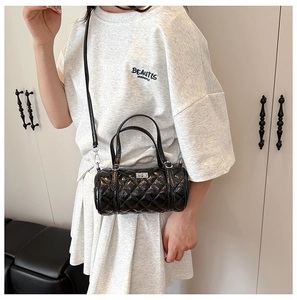 Détail du sac barillet en cuir verni noir matelassé avec finitions argentées