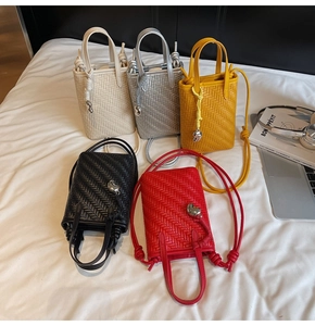 Macro shot of colorful woven mini crossbody bags with heart charms in five colors