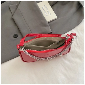 Detail of red patent leather baguette bag featuring silver chain and beige fabric lining
