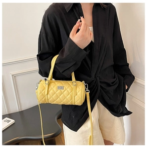 Détail du sac cylindre jaune matelassé avec ferrures argentées et bandoulière en cuir