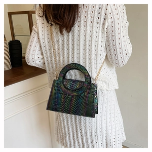 Detail of crocodile pattern handbag with gold chain strap on a white knit dress