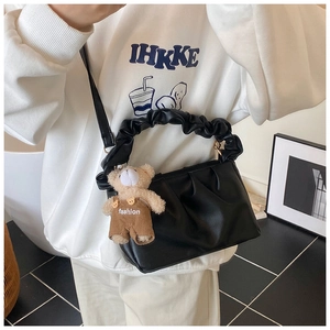 Detail of black pleated cloud bag with stylish leather texture and cute bear pendant