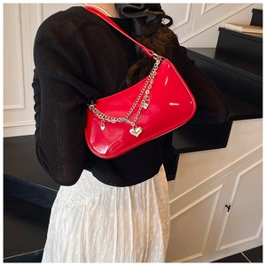 Detail of red patent leather shoulder bag with silver heart and lock chain charms