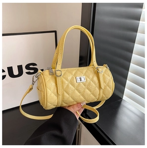 Gros plan du sac cylindre matelassé jaune avec fermoir rotatif argenté et texture délicate