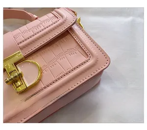 Detail showing pink crocodile embossed leather texture and gold square buckle closure
