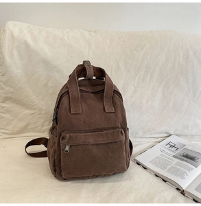 Close-up of deep brown canvas backpack with sturdy double handles and front zipper pocket