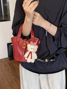 Red glossy leather bucket bag with metallic buckle and cute white plush bear pendant