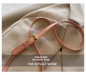 Detail of pink leather shoulder strap with golden adjustable buckle on beige suit fabric