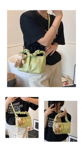 Close-up of light green pleated handbag with cute bear charm and ruched handle detail