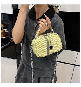 Détail du sac à main vert-jaune à texture tressée avec pompons argentés et chaîne