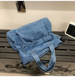 Detail of vintage blue denim tote bag with functional front flap pocket and washed texture