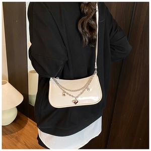 Detail of cream white leather crescent bag with silver chain and heart charm