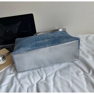Dettaglio della borsa tote in denim blu con finiture argento e fondo rinforzato
