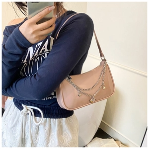 Detail of pink shoulder bag with silver metal chain, heart charms and zipper closure