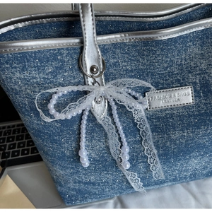 Dettaglio borsa tote in denim blu con bordi argentati, paillettes e fiocco di perle