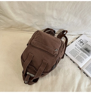 Detail of dark brown canvas backpack with metal zippers and retro multi-pocket design