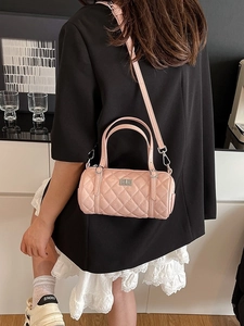 Sac Boston cylindrique rose matelassé avec fermoir argenté porté avec une tenue élégante