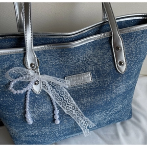 Dettaglio borsa tote in denim glitterato blu con manici argento e fiocco in pizzo
