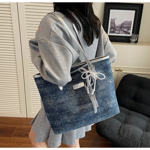 Dettaglio della borsa tote in denim blu con paillettes luccicanti e fiocco di perle e pizzo