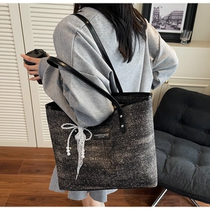 Dettaglio della borsa tote in tweed con fiocco di perle, pizzo e manici in pelle