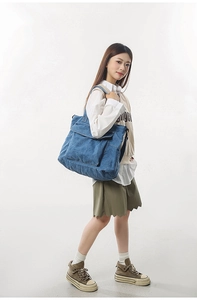 Front flap pocket detail on large denim tote bag for students and commuters