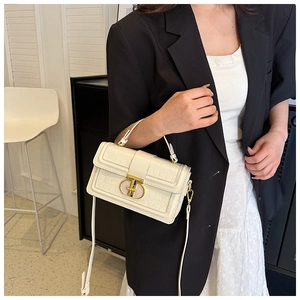 Close-up of cream white crocodile texture handbag with gold swivel lock and leather strap
